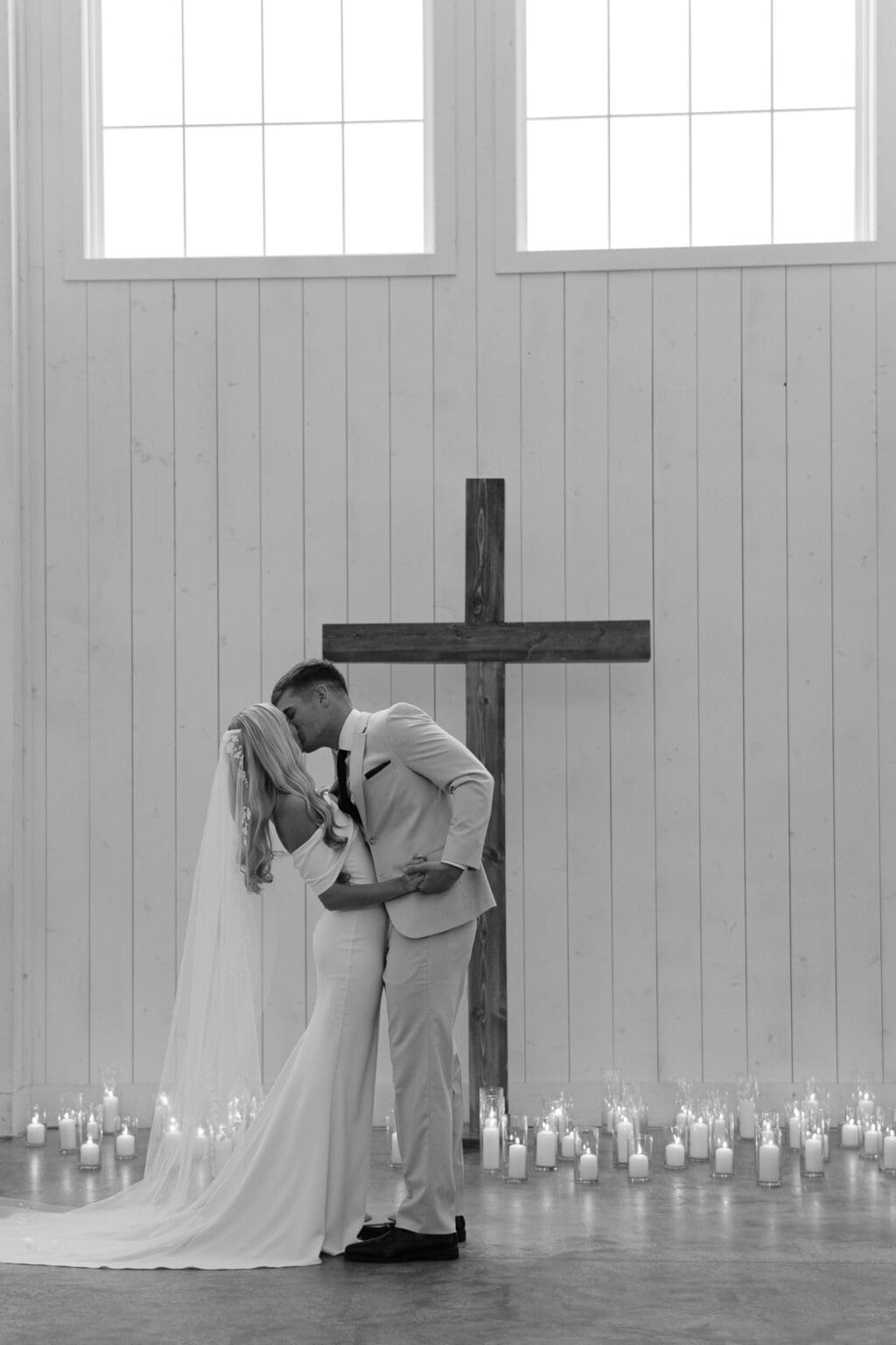 couple dressed in wedding attire and kissing with candlelight around them