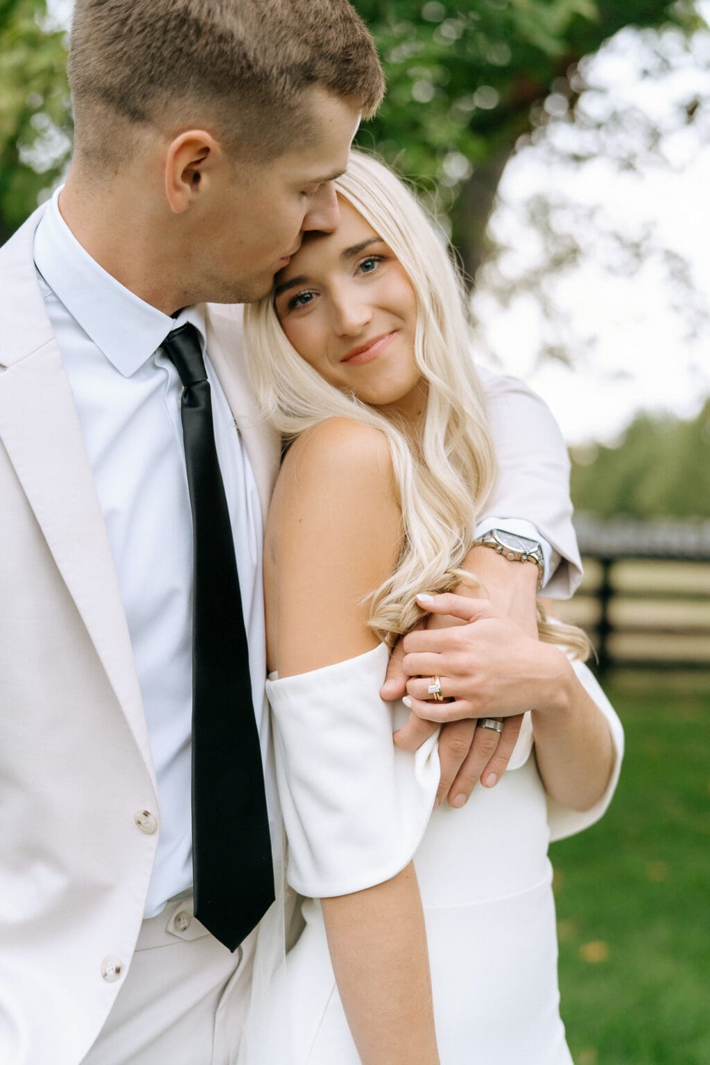 groom holding bride with trees around them