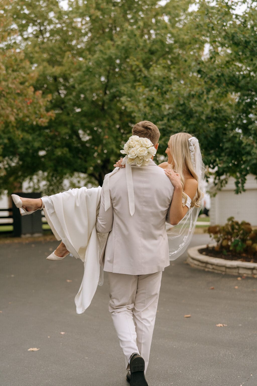 groom carrying bride and walking through trees